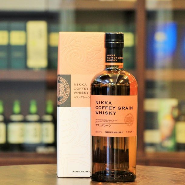 Bottle of Nikka Coffey Whisky next to the box with shelves of whisky in the background - best Japanese whisky for cocktails