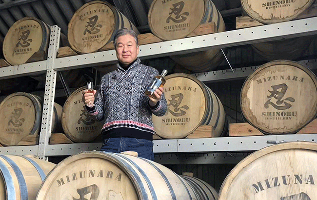 Shinobu head distiller posing around barrels.